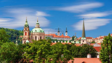 Prague centre historique vieille skyline avec église de Saint-Nicolas belle coupole baroque et tour de l'horloge parmi les arbres
