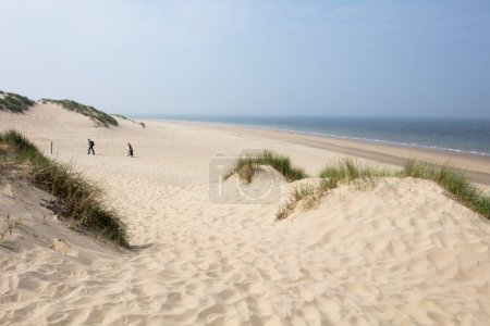 Dünen und Nordseeküste mit zwei unscharfen (Bewegungsunschärfen) Spaziergängern in Burgh Haamstede in den Niederlanden