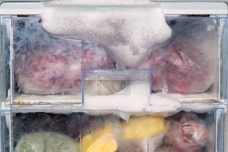 Foto de El hielo se congeló en el congelador porque la puerta no estaba cerrada. Descongelar el refrigerador. descongelar el congelador. - Imagen libre de derechos