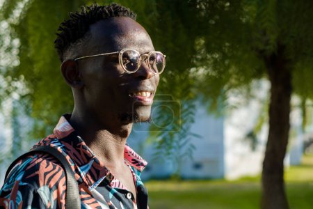 Photo for Keep your head up and achieve all your goals, young african man with glasses, standing outdoors thinking and smiling. - Royalty Free Image