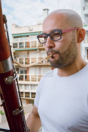 Photo for Young latino man, venezuelan musician of the simon bolivar symphony orchestra, immigrant in argentina, vertical image close-up playing the bassoon at home. - Royalty Free Image