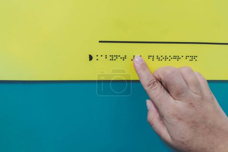 Primer plano de la mano de una mujer leyendo la palabra "fluorografía" en braille. Ceguera. Día Mundial del Braille. La mano de una mujer toca el bulto de una señal. Día de los Ciegos y los Discapacitados. Día mundial de la vista