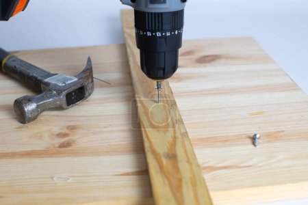 Foto de Una pistola de tornillo con un martillo de metal sobre fondo de madera. Concepto de reparación. - Imagen libre de derechos