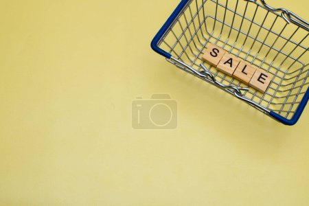 Téléchargez les photos : Vente Black Friday concept de shopping. Panier avec la description "Vente" sur fond jaune avec espace de copie - en image libre de droit