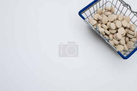 Photo for Multivitamin tablets in shopping basket on white - Royalty Free Image