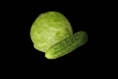Vegetable set of cabbage and green cucumber on a black background. Axonometric view on the right.