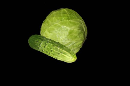 Vegetable set of cabbage and green cucumber on a black background. Axonometric view on the left.