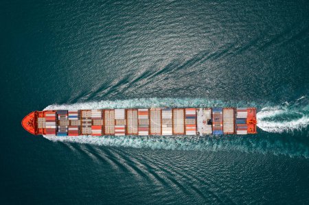 cargo container ship full speed sailing in sea import and export business and industry logistic goods transportation of international by container ship in ocean fright aerial top view photograph from drone 