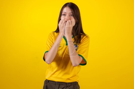 Téléchargez les photos : Montréalaise portant la chemise officielle de l'équipe brésilienne de football dans la Coupe Qatar 2022 et avec le drapeau du Brésil en photo studio. ventilateur brésilien. - en image libre de droit