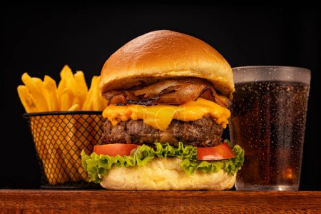 Hamburger accompanied by fries and soda in a studio photo with brown and black wood