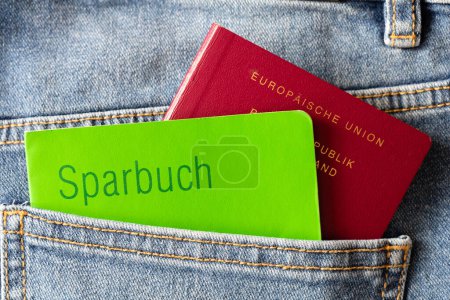 Photo for Old-fashioned green savings book and German passport in the blue jeans pocket. - Royalty Free Image