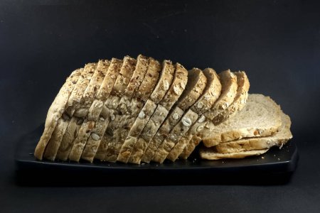 Photo for Loaf of multigrain bread on black platter isolated on black background. sliced bread - Royalty Free Image