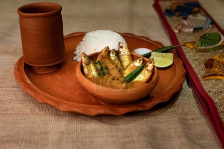 Photo for Mourala fish or indian carplet fish curry served with rice in earthenware on beige jute textured background. selective focus. top view - Royalty Free Image