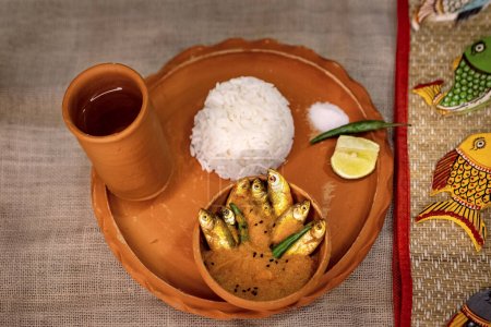 Photo for Mourala fish or indian carplet fish curry served with rice in earthenware on beige jute textured background. selective focus. top view - Royalty Free Image