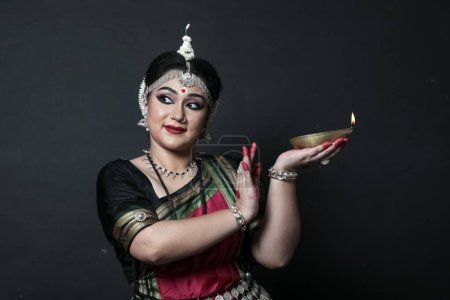 Foto de Bailarina india de odishi que celebra Diwali o deepavali, festividad de luces en el templo. Manos femeninas sosteniendo lámpara de aceite. - Imagen libre de derechos