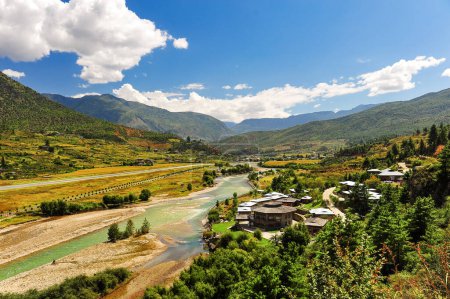 Foto de Una vista panorámica del aeropuerto y el valle del Paro, Bután. Paisaje con Montaña, río, prados verdes y tierras agrícolas, cielo azul con nubes blancas. - Imagen libre de derechos
