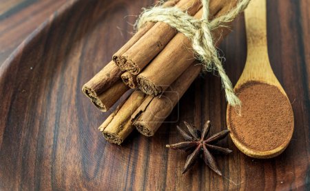 Organic Raw Brown cinnamon sticks Anise star spice fruits and seeds on old wooden table wood stump trunk outdoor walnut plate spoon closeup macro Food Background Vintage Selective Focus