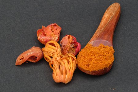 Mace spice powder on a wooden spoon on black background 