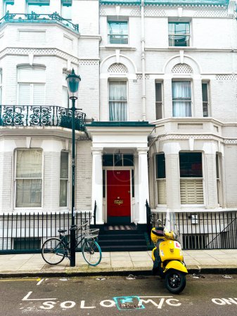 Téléchargez les photos : Rue résidentielle à Chelsea à Londres avec sakura rose en fleurs. Les maisons confortables de Londres ont l'air confortables sous le ciel bleu. Quartier résidentiel parfait pour un style de vie idyllique - en image libre de droit