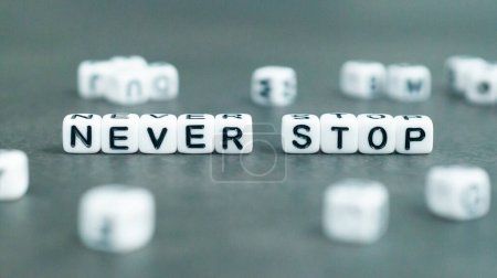 Photo for Never stop slogan in white block letter beads. Success and self confidence concept. High quality photo - Royalty Free Image