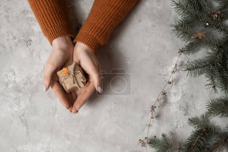 Téléchargez les photos : Vue du dessus des mains d'une fille enveloppant un cadeau de Noël ou d'anniversaire et le décorer avec des étiquettes, en arrière-plan un arbre de Noël et des lumières, le concept de préparation pour la nouvelle année, joyeux Noël, nouvelle année 2023 - en image libre de droit