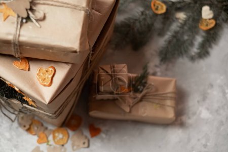 Téléchargez les photos : Emballage des cadeaux du Nouvel An, branches de sapin et papier d'emballage artisanal se trouvent sur la table et enveloppé cadeaux du Nouvel An sur un fond gris, arbres de Noël en papier, préparation pour Noël, concept d'emballage cadeau - en image libre de droit