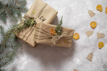 Téléchargez les photos : Emballage des cadeaux du Nouvel An, branches de sapin et papier d'emballage artisanal se trouvent sur la table et enveloppé cadeaux du Nouvel An sur un fond gris, arbres de Noël en papier, préparation pour Noël, concept d'emballage cadeau - en image libre de droit