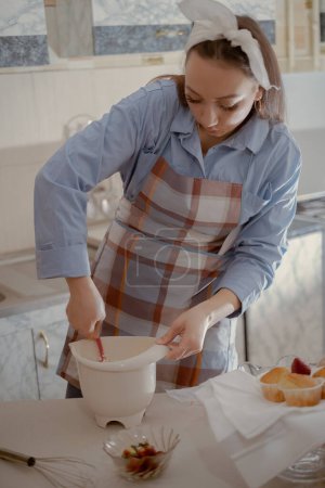 Foto de Una pastelera femenina prepara glaseado para magdalenas. Disfrute del arte de hornear en casa con este chef de pastelería casero elaborando deliciosas golosinas en casa. - Imagen libre de derechos