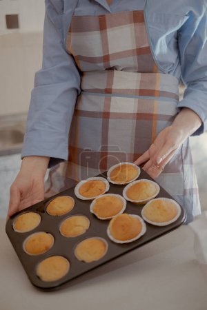 Foto de Una pastelera tiene pastelitos recién horneados, mostrando su pastelería casera. Abrace el arte de hornear en casa con esta imagen de un chef experto en pastelería que trabaja desde casa. - Imagen libre de derechos