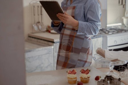 A female pastry chef holds a tablet for managing orders, representing homemade baking. Experience the essence of small-scale, eco-friendly baking with gluten-free and sugar-free products, promoting healthy eating.
