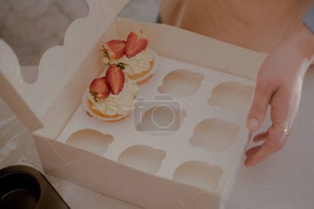Eine Konditorin verpackt Cupcakes in Verpackungen für den Versand an Kunden und präsentiert hausgemachtes Backen. Erleben Sie die Essenz des kleinen, umweltfreundlichen Backens mit gluten- und zuckerfreien Produkten und fördern Sie eine gesunde Ernährung.