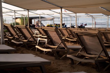 Reihen von Strandliegen am Meer, die Resorts, Strandtouren, Produkte / Dienstleistungen sowie Aktivitäten und Unterhaltung am Strand fördern.