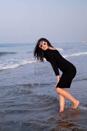 A joyful girl runs along the seaside, attracting tourists to coastal resorts and hotels, highlighting the beauty and tranquility of the coastline.