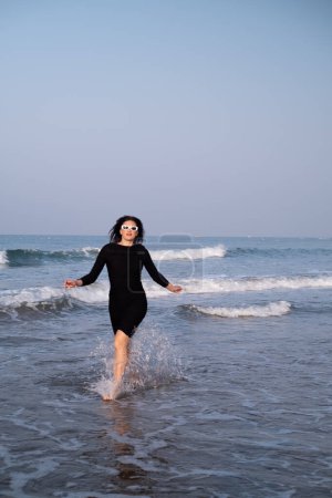 Foto de Una chica alegre corre a lo largo de la costa, atrayendo turistas a resorts y hoteles costeros, destacando la belleza y tranquilidad de la costa. - Imagen libre de derechos