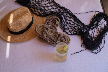 Straw hat, flip-flops, and cocktail glass: essentials for seaside resorts, beachwear, and vacation excursions. Embrace coastal style and relaxation.
