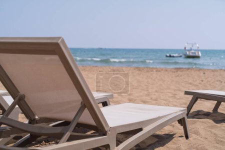 Téléchargez les photos : Détente au bord de la plage : chaise longue donnant sur la mer. Parfait pour les hôtels de villégiature, les vacances en famille et les escapades balnéaires. Plongez dans la tranquillité. - en image libre de droit