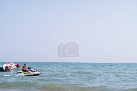Photo for Man in life jacket rides jet ski in the sea, representing extreme sports and guided tours. Experience adrenaline-packed adventures with tourist services. - Royalty Free Image