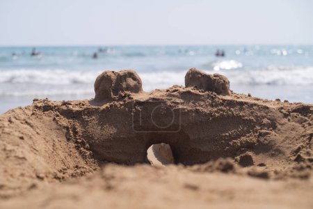 Sandcastle junto al mar mientras las familias se relajan y juegan. Perfecto para representar vacaciones en la playa, atracciones locales y experiencias turísticas memorables.