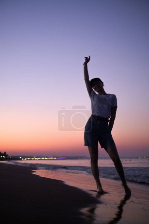 Mädchen steht bei Sonnenaufgang am Meer und verkörpert Ruhe und Gelassenheit. Förderung von Tourismus, Resorts, gesundem Lebensstil und Outdoor-Sport.