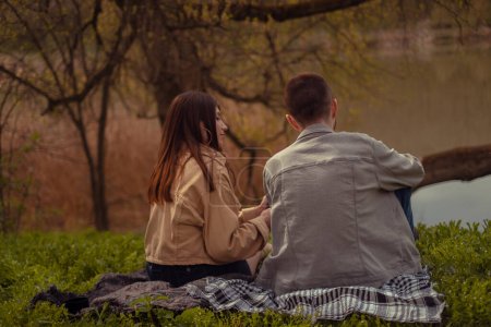 Una joven pareja en una cita en el arboreto, con la espalda a la cámara, disfrutando acampar en el bosque, pasar tiempo al aire libre, y abrazar la belleza de la naturaleza. Día de San Valentín