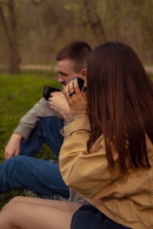 Una joven pareja conversando al aire libre, pasando tiempo juntos en el camping, calentándose con bebidas calientes, vertiendo café desde un termo.