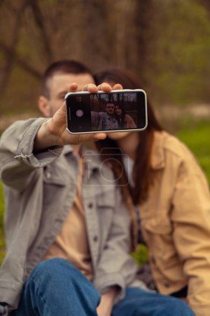 A young couple takes a photo on a mobile phone, capturing beautiful and memorable moments. Applications for photo editing. Valentine's Day