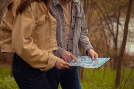 Ein Junge und ein Mädchen verloren sich im Wald und hielten eine Landkarte in der Hand. Mit Führungen und Waldwegen. Ausflugsprogramme und Reisen.
