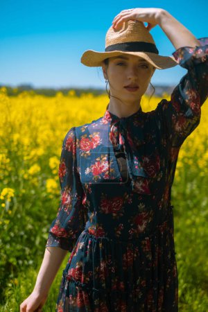 Young woman in field with straw hat and flower bouquet, summer accessories, beach products, vacation items, or resort services, creating atmosphere of summer relaxation and comfort.
