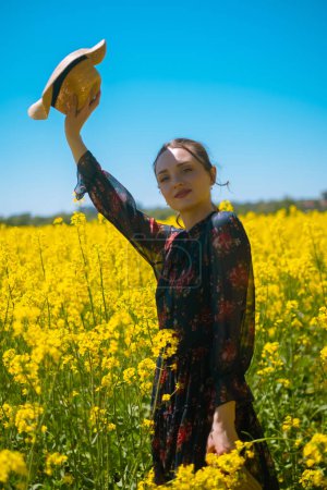 Young woman in field with straw hat and flower bouquet, summer accessories, beach products, vacation items, or resort services, creating atmosphere of summer relaxation and comfort.