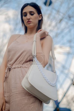 White eco-leather bag, cruelty-free fashion choice, woman holding bag over shoulder, promoting animal-free alternatives.