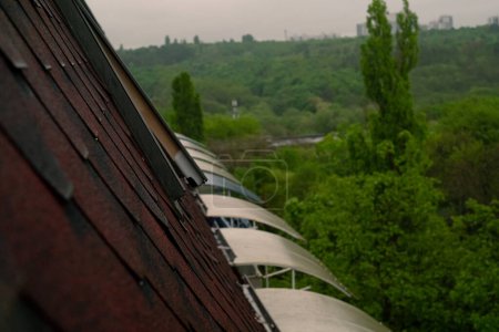 Un toit rouge d'un bâtiment, présentant des matériaux de toiture respectueux de l'environnement et résistants aux intempéries. Insistez sur l'éco-conscience de votre entreprise dans la publicité.