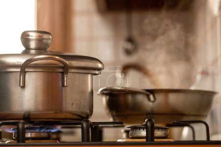 Téléchargez les photos : Cuire avec de vieilles casseroles sur la cuisinière avec de la vapeur d'eau bouillante. Ambiance vintage - en image libre de droit