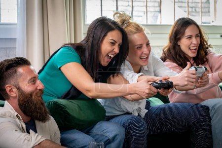 Foto de Grupo de amigos divirtiéndose y riéndose mientras juegan videojuegos. Top competencia entre las niñas - Imagen libre de derechos