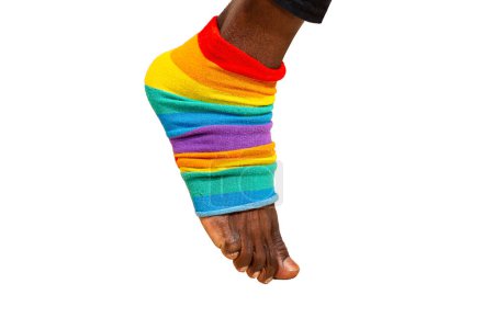 Foto de Pie de un hombre africano con calcetín de color arco iris. Polaina de color iris aislada sobre fondo blanco. LGBT, concepto lgbtq - Imagen libre de derechos